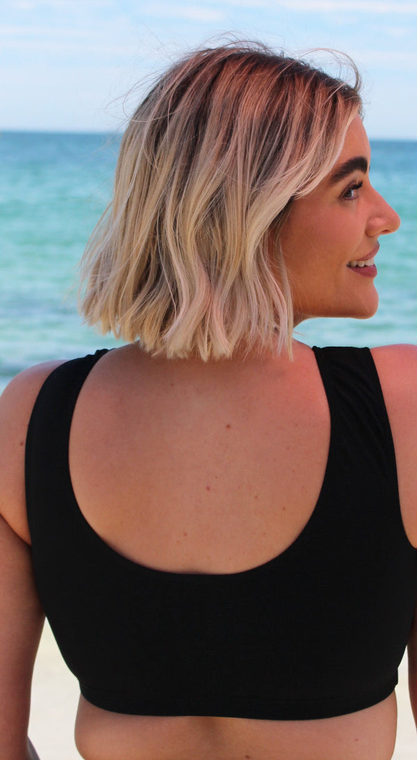 Woman wearing a black sports bra with a beach