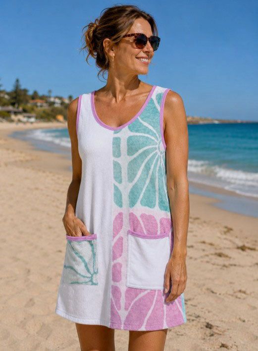 woman towel dress wearing a sleeveless white beach cover-up dress with pastel pink and mint green abstract patterns