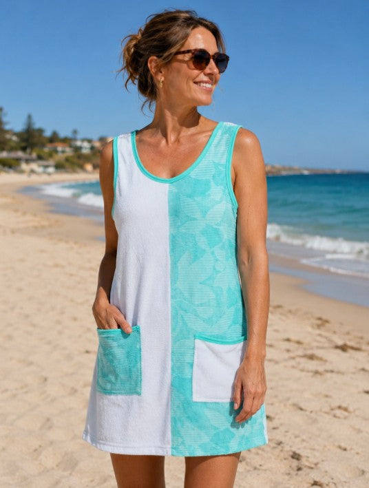 A woman wearing a Viva sleeveless split-color beach cover-up dress with white and mint green panels,