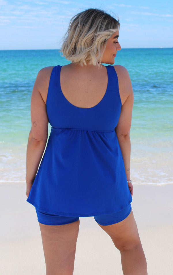 Woman wearing a blue swimsuit with a beach and ocean background