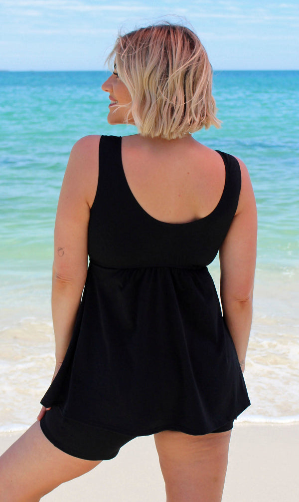 Woman wearing a black dress standing on a beach 