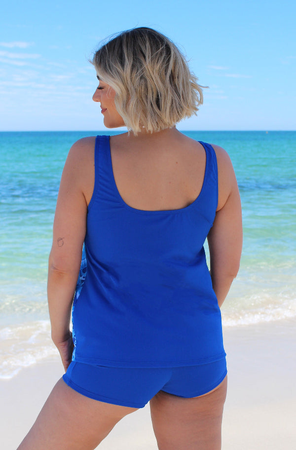 Woman wearing a blue swimsuit standing on a beach 