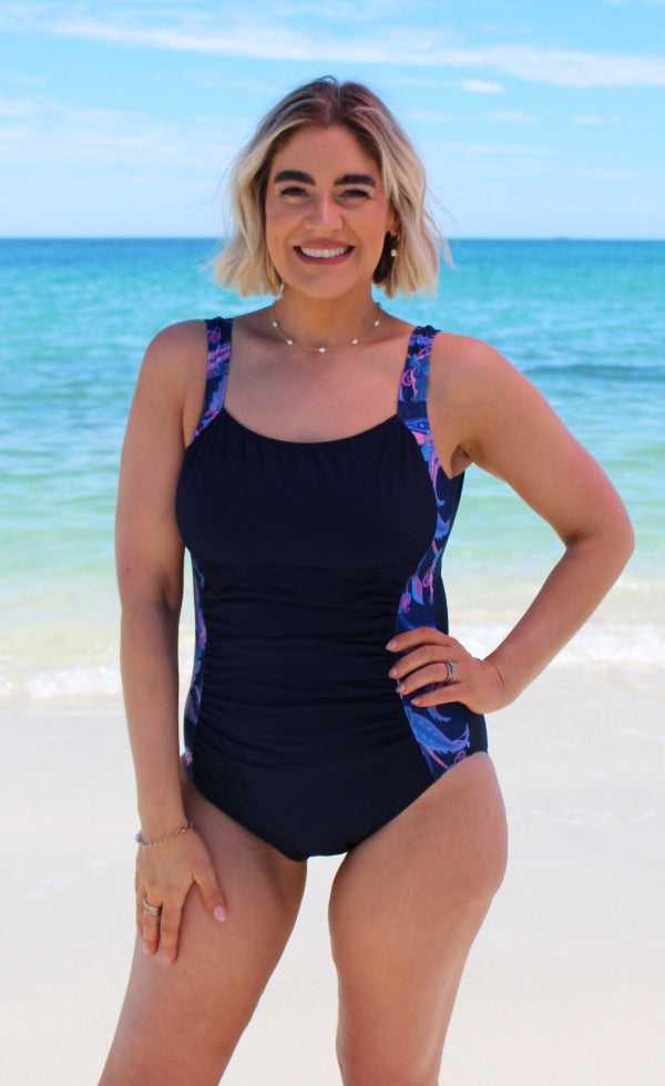 Woman wearing a black swimsuit with colorful straps on a beach